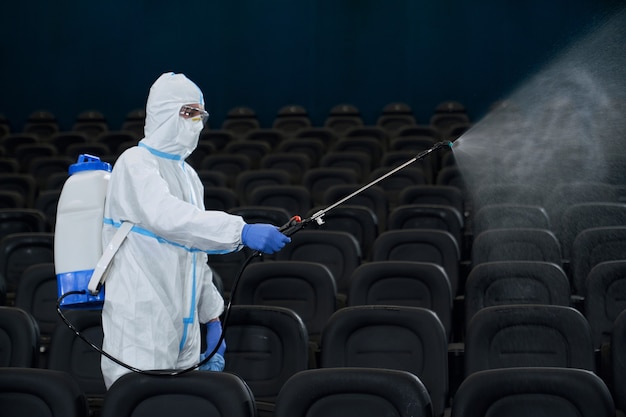 Uomo con attrezzature speciali per la disinfezione nel cinema