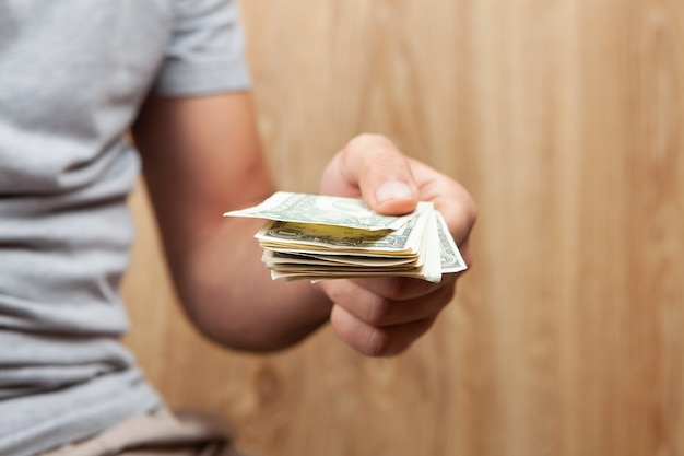 Uomo con banconote da un dollaro su sfondo di legno