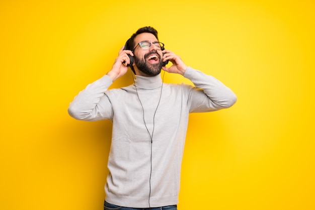 Uomo con barba e collo alto ascoltando musica con le cuffie