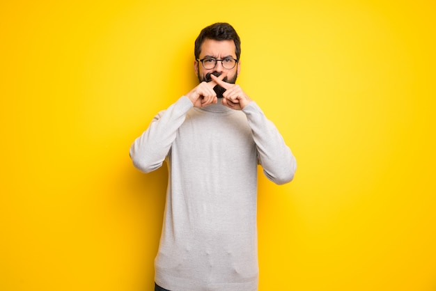 Uomo con barba e collo alto mostrando un segno di silenzio gesto