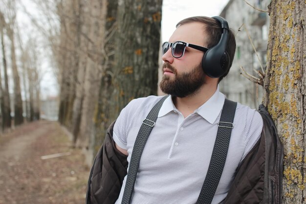 Uomo con barba e cuffie nel parco