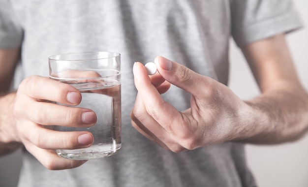 Uomo con bicchiere d'acqua e tablet.