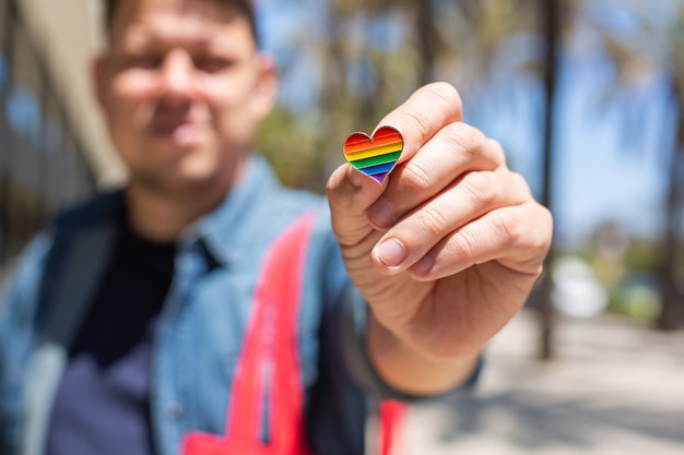 Uomo con borsa riutilizzabile arcobaleno e mese dell'orgoglio distintivo lgbt