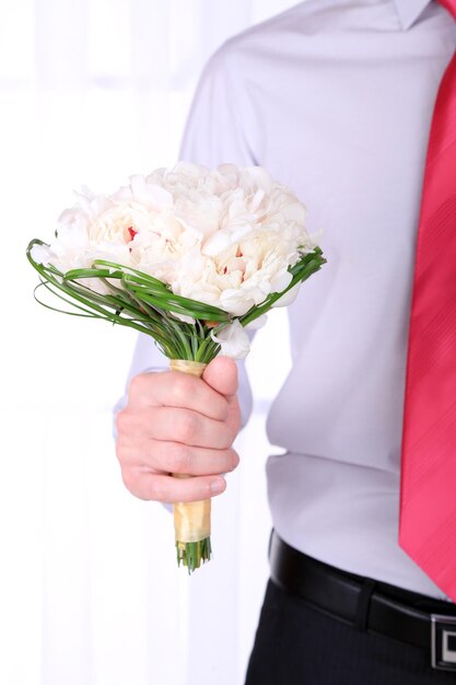 Uomo con bouquet da sposa su sfondo chiaro