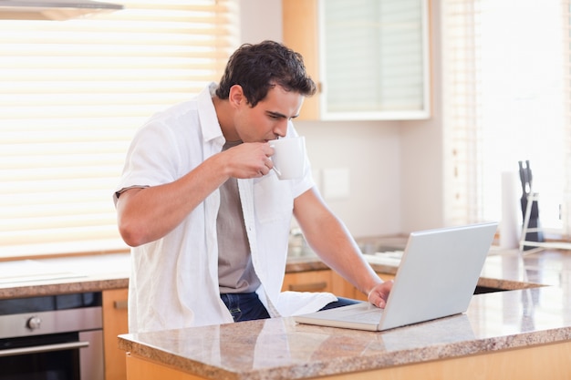 Uomo con caffè e laptop in cucina