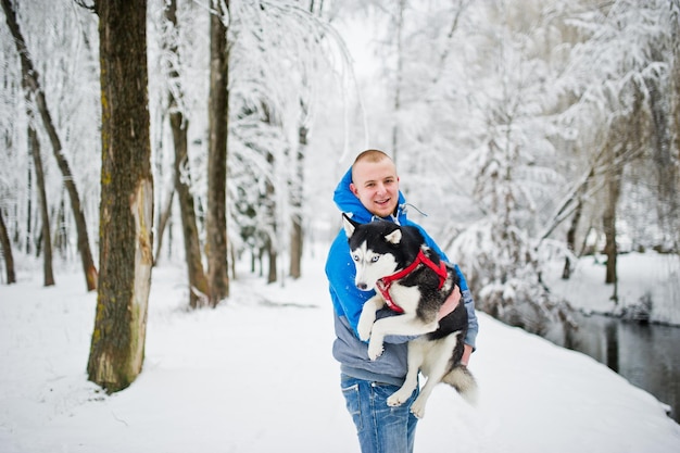 Uomo con cane husky al parco innevato invernale.