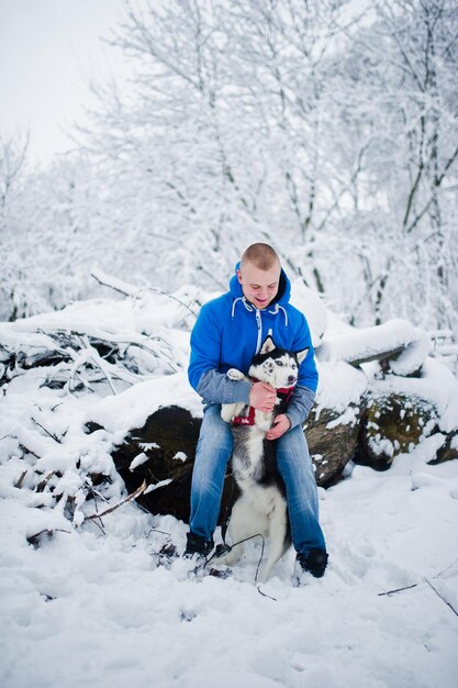 Uomo con cane husky al parco innevato invernale.