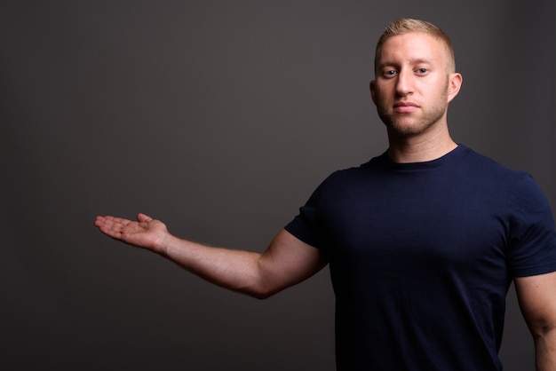 Uomo con capelli biondi sulla parete grigia