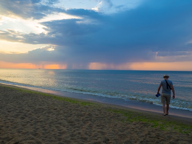 Uomo con cappello che va sulle onde del mare all'alba