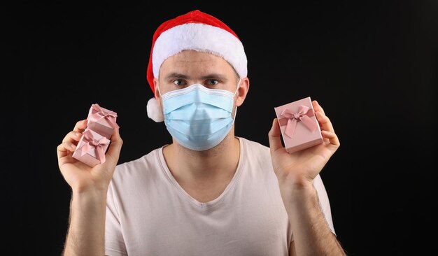 Uomo con cappello da Babbo Natale e maschera medica su sfondo nero