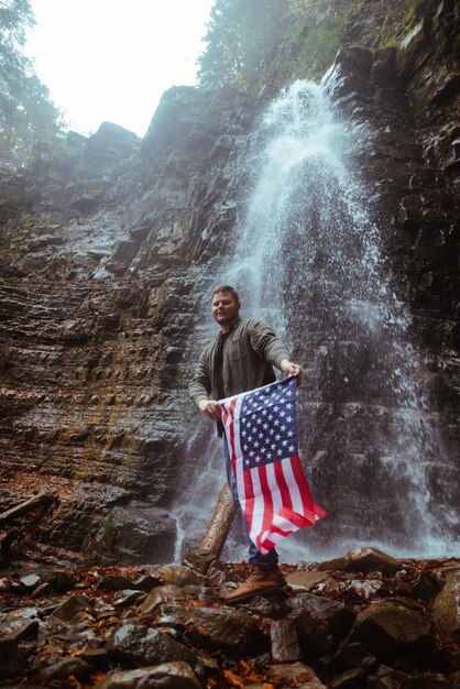 Uomo con cascata bandiera usa sullo sfondo