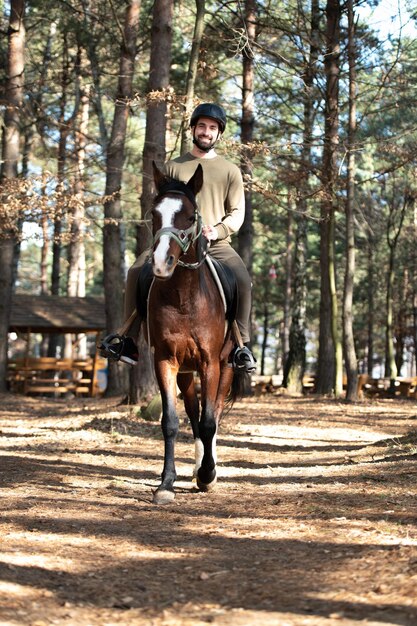 Uomo con casco a cavallo nella foresta