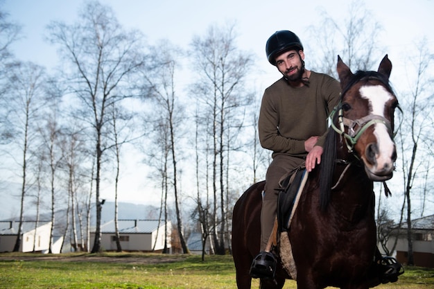 Uomo con casco a cavallo nella foresta