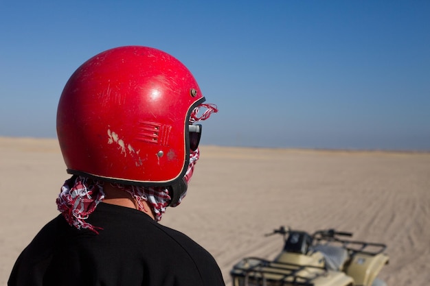 Uomo con casco accanto a un ATV nel deserto