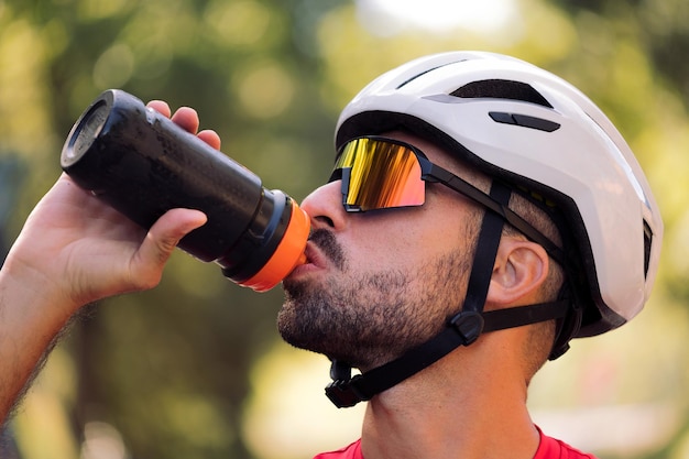 Uomo con casco e occhiali da ciclismo acqua potabile