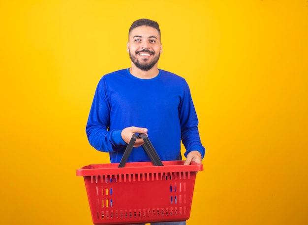 Uomo con cesto supermercato su sfondo giallo