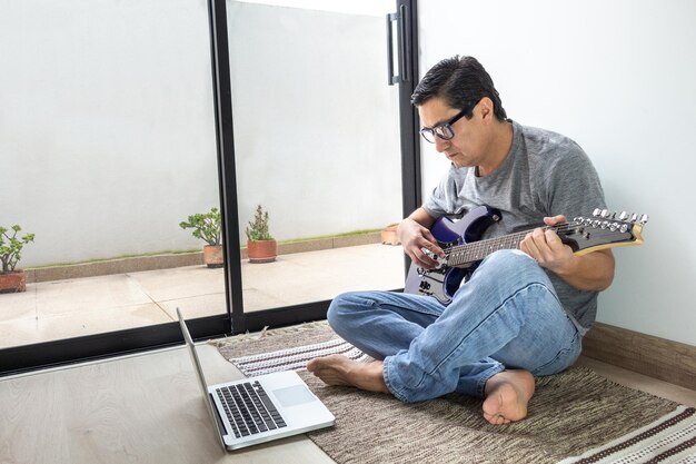 Uomo con chitarra elettrica in classe virtuale a casa