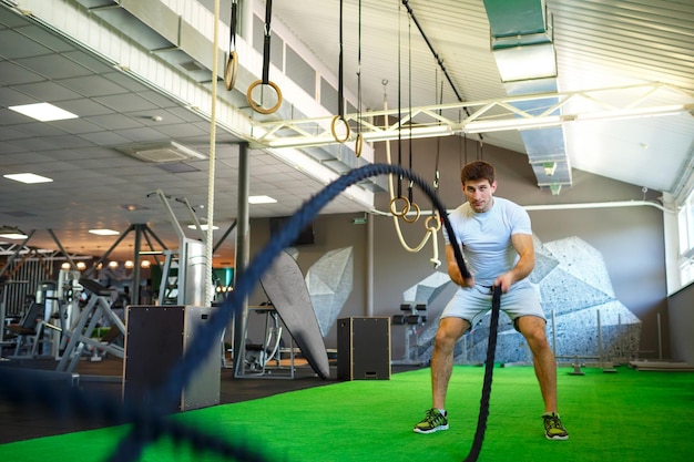 Uomo con corda da battaglia nella palestra di allenamento funzionale