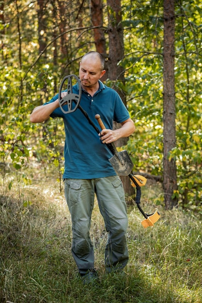 Uomo con dispositivo elettronico metal detector, sfondo esterno.