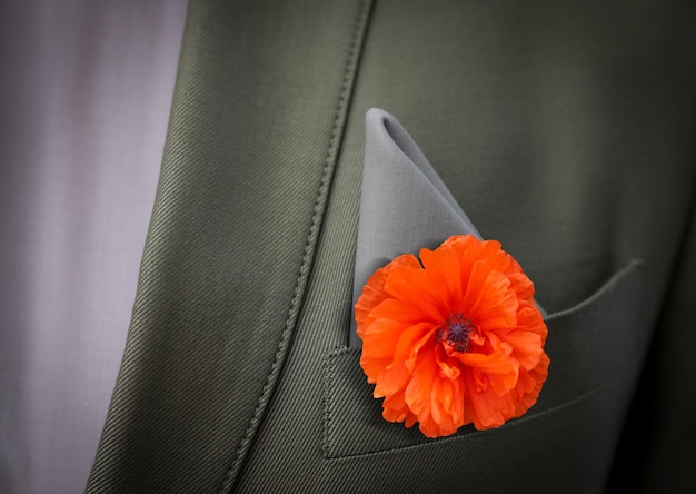 Uomo con fiore di papavero rosso nella tasca del vestito vista in primo piano Simbolo del ricordo