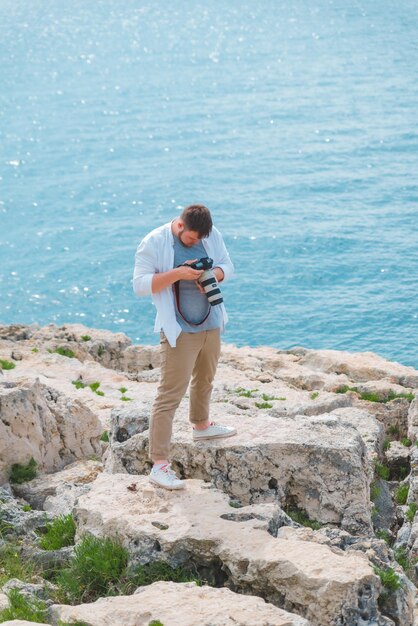 Uomo con fotocamera dslr professionale che scatta foto dello spazio della copia in riva al mare