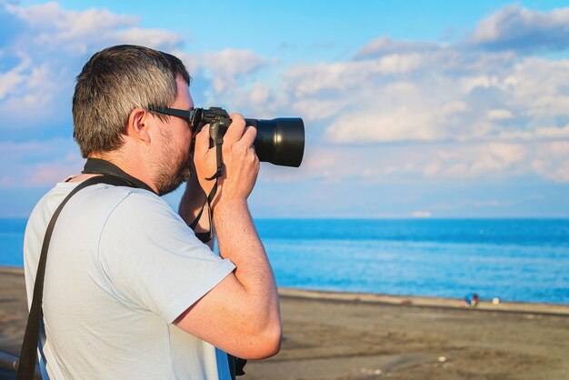 Uomo con fotocamera per scattare foto della spiaggia del Mar Mediterraneo a Santa Teresa di Riva vicino a Messina, Sicilia, Italia