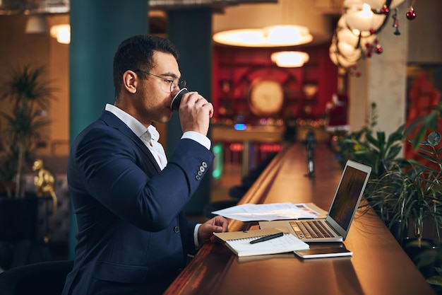 Uomo con gli occhiali che beve un sorso di caffè