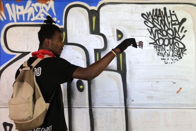 Uomo con gli occhiali da sole e in piedi contro il muro con i graffiti