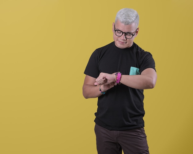 Uomo con gli occhiali in attesa in piedi e guardando il suo smartwatch