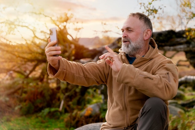 uomo con gli stivali che raggiunge la destinazione e scatta foto al telefono nel Peak District