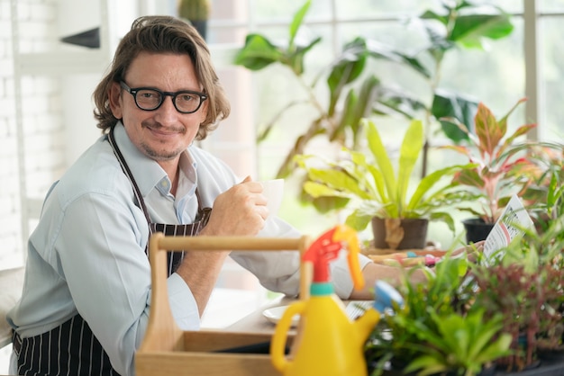 uomo con grembiule in serra a bere caffè