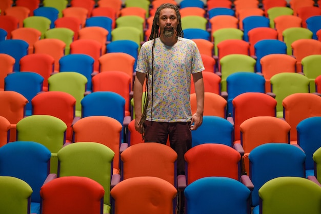 Uomo con i dreadlocks in piedi tra le sedie