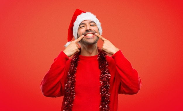 Uomo con i vestiti rossi che celebra le feste di Natale che sorridono mentre indicando bocca
