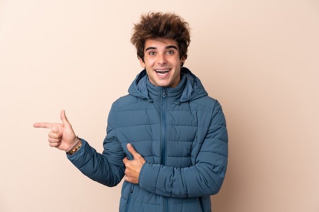 Uomo con il cappotto di inverno sopra la parete isolata