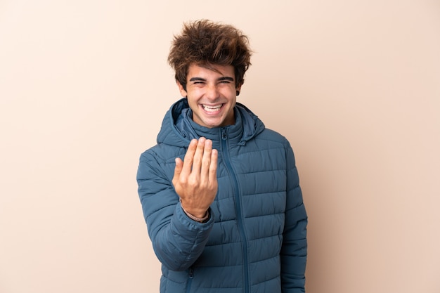 Uomo con il cappotto di inverno sopra la parete isolata