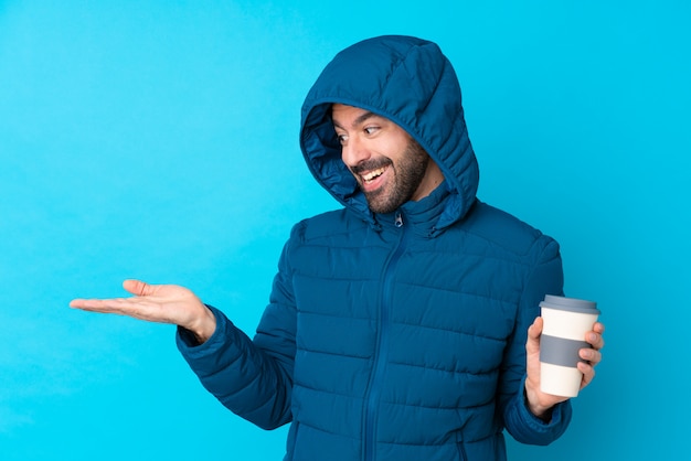 Uomo con il cappotto di inverno sopra la parete isolata