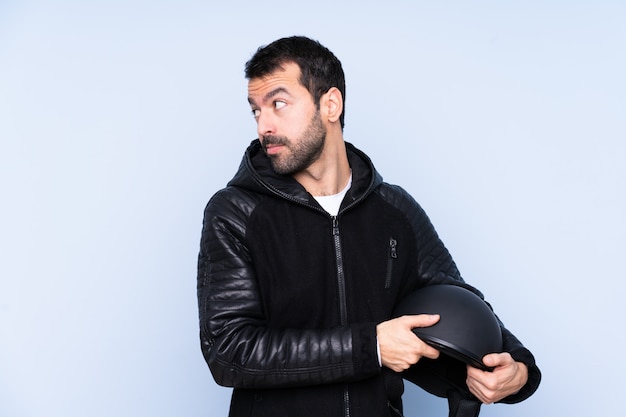 Uomo con il casco del motociclo sopra la parete isolata