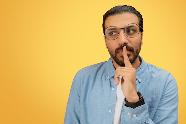 Uomo con il dito sulle labbra in camicia denim