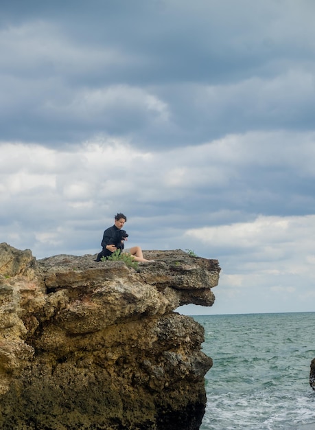 uomo con il suo cucciolo seduto in una baia a guardare il mare