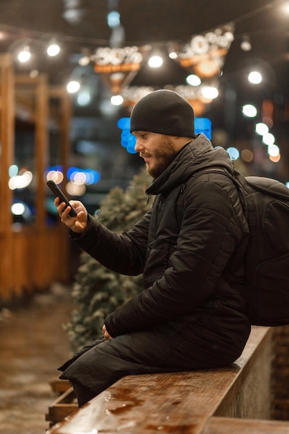 Uomo con il telefono. città notturna. inverno. shopping, videocomunicazione.