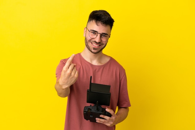 Uomo con in mano un telecomando drone isolato su sfondo giallo che fa un gesto imminente