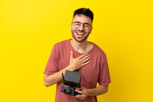 Uomo con in mano un telecomando drone isolato su sfondo giallo che sorride molto