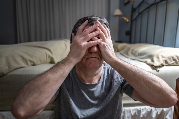 Uomo con insonnia seduto per terra e con le mani sul viso disperato