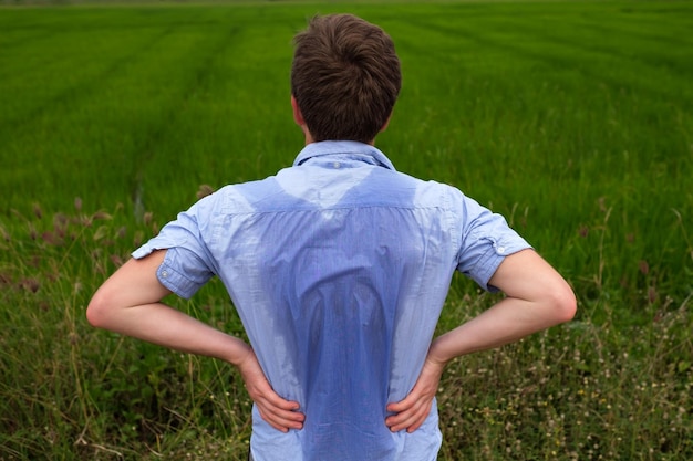 Uomo con iperidrosi che suda molto male sotto l'ascella in camicia blu isolata su grigio