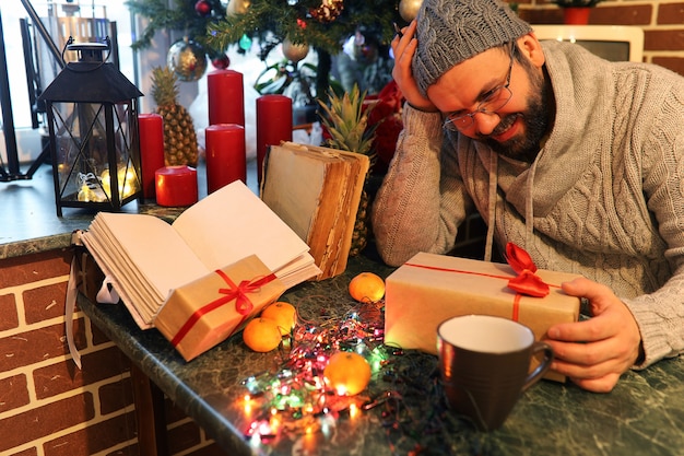 Uomo con la barba che scrive regali di natale su un tavolo con vecchi libri