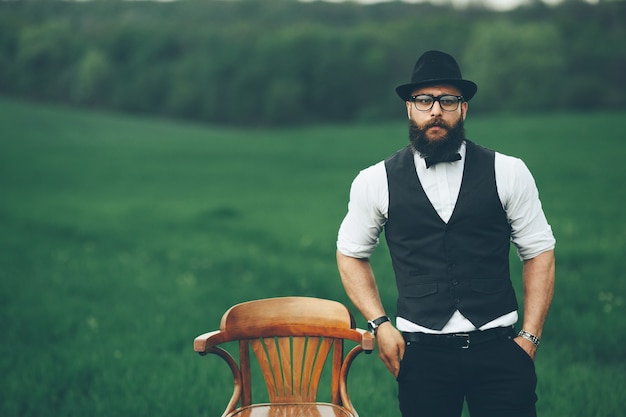 Uomo con la barba, pensando nel campo vicino alla sedia