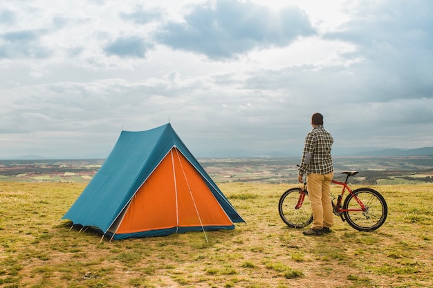 Uomo con la bici in piedi accanto alla tenda