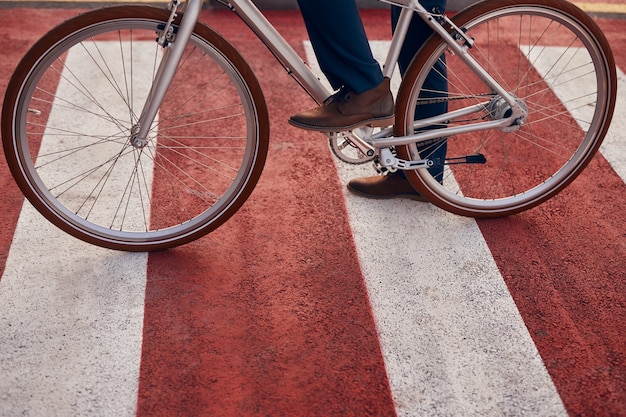 Uomo con la bicicletta che attraversa la strada in città