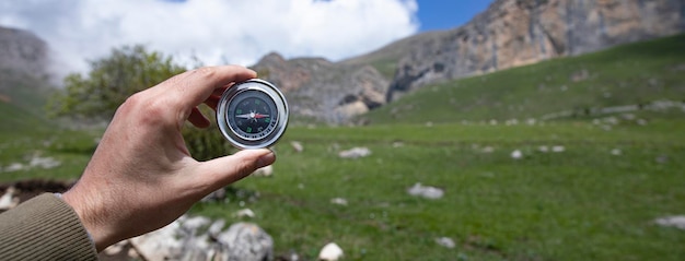Uomo con la bussola in mano sulla strada delle montagne