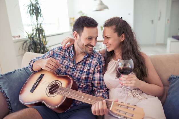 Uomo con la chitarra acustica che canta per la donna sorridente